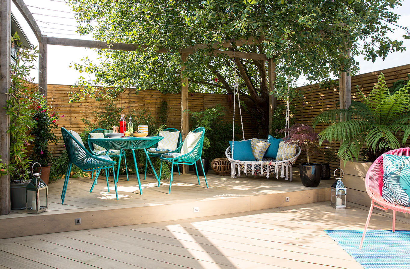 The Garden Room, a decked courtyard garden, featuring composite decking, exotic planting, garden room, pergola, swing seat, dining area, modern garden lighting and container pond. Designed by April House – Award Winning Cotswolds Garden Design