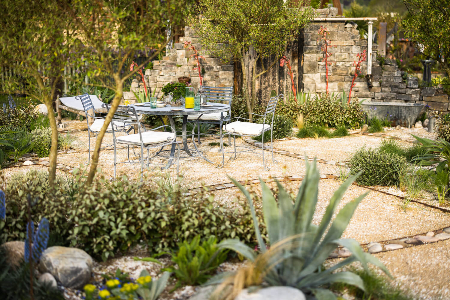 The Home Away Garden, a drought tolerant RHS award-winning show garden with a Harrod Horticulture steel table and chairs. Designed by April House – Award Winning Cotswolds Garden Design