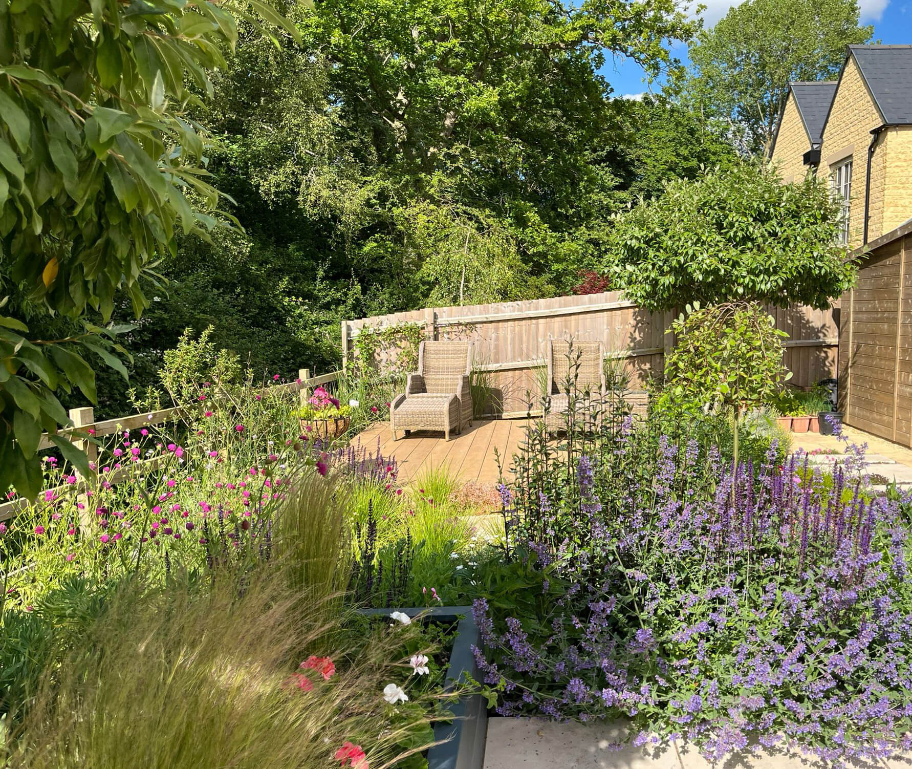 The Naturalistic New Build Garden, A new build garden plot redesigned to harness the view featuring planting to echo the landscape beyond, a sundeck and paving interplanted with thyme. Designed by April House – Award Winning Cotswolds Garden Design