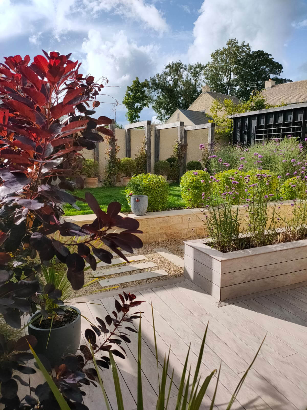 The Office Garden, a garden designed for home working, featuring garden office, pergola, composite decking, lawn, sundeck, dining area and hot tub. Designed by April House – Award Winning Cotswolds Garden Design