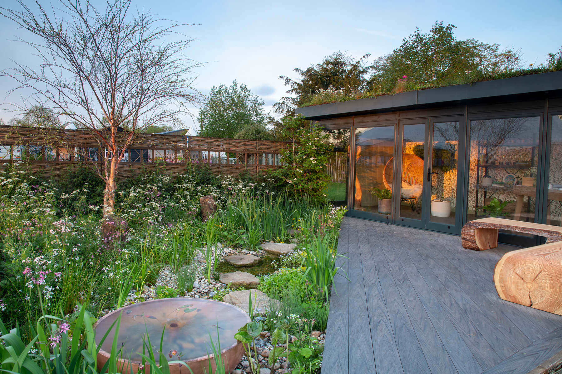 The Hide Garden, an RHS Malvern 2022 Silver Gilt medal winning garden, which features river pond, natural planting, composite decking, garden studio and willow fencing. Designed by April House – Award Winning Cotswolds Garden Design